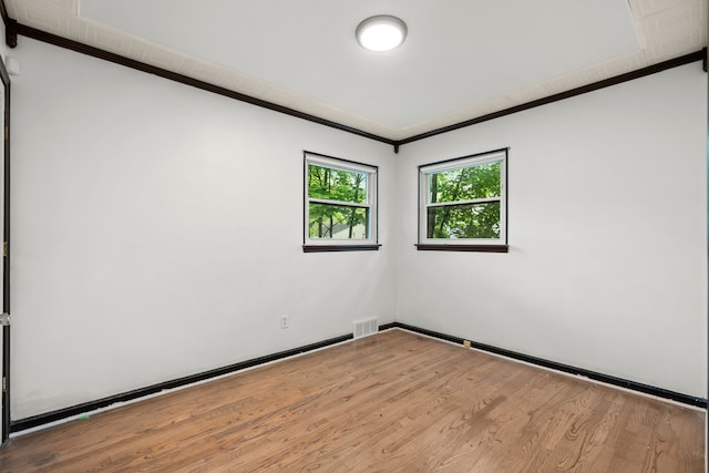 empty room featuring ornamental molding, wood finished floors, and baseboards