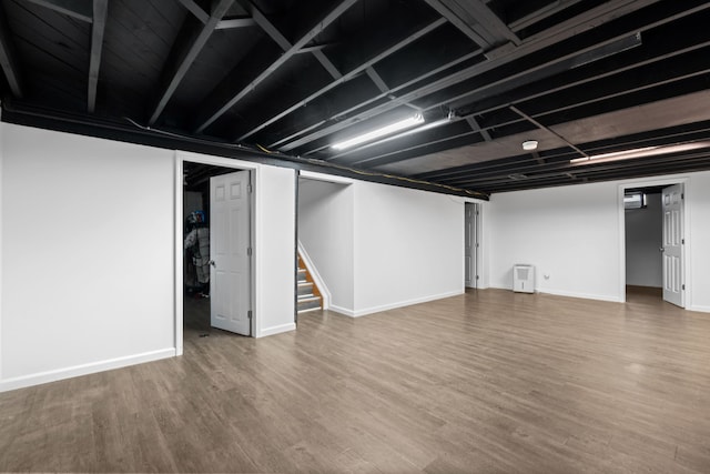 finished basement featuring wood finished floors, baseboards, and stairway