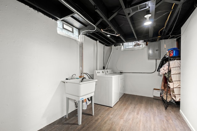 clothes washing area featuring washing machine and clothes dryer, electric panel, plenty of natural light, and light wood finished floors