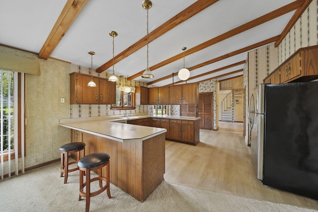 216 Wickenham Dr, Spring Arbor, MI 49283 - kitchen with freestanding refrigerator, a peninsula, plenty of natural light, brown cabinetry, and wallpapered walls