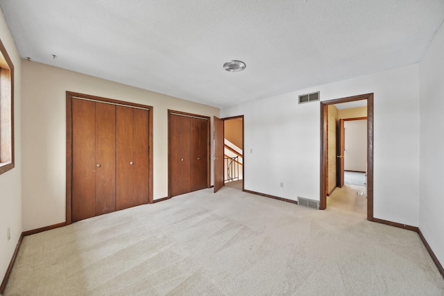 216 Wickenham Dr, Spring Arbor, MI 49283 - unfurnished bedroom featuring multiple closets, baseboards, light colored carpet, and a textured ceiling