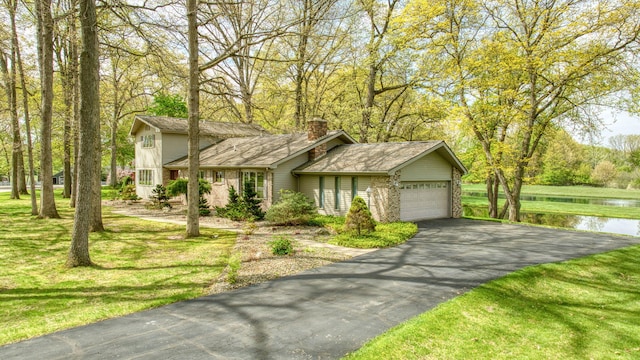 216 Wickenham Dr, Spring Arbor, MI 49283 - view of front facade featuring a garage, driveway, a chimney, a water view, and a front lawn