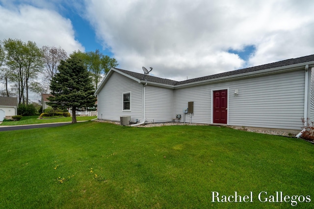 rear view of property featuring a lawn and central AC