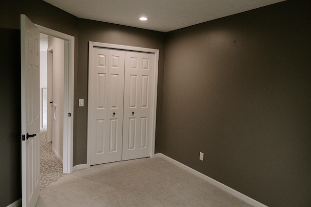unfurnished bedroom with light carpet, a closet, baseboards, and recessed lighting