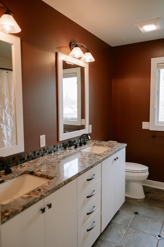 bathroom with double vanity, toilet, and baseboards