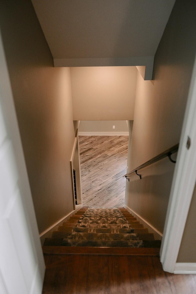stairway with wood finished floors and baseboards