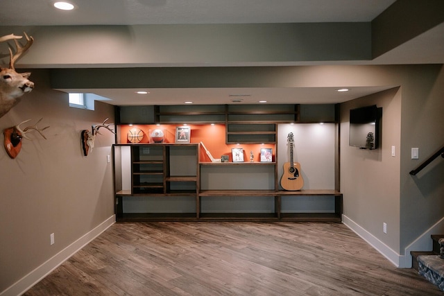basement featuring baseboards, wood finished floors, recessed lighting, and stairs