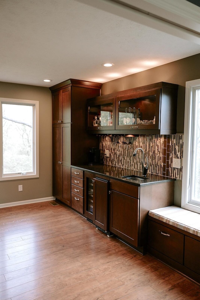 indoor wet bar with decorative backsplash, light wood-type flooring, baseboards, recessed lighting, and wine cooler