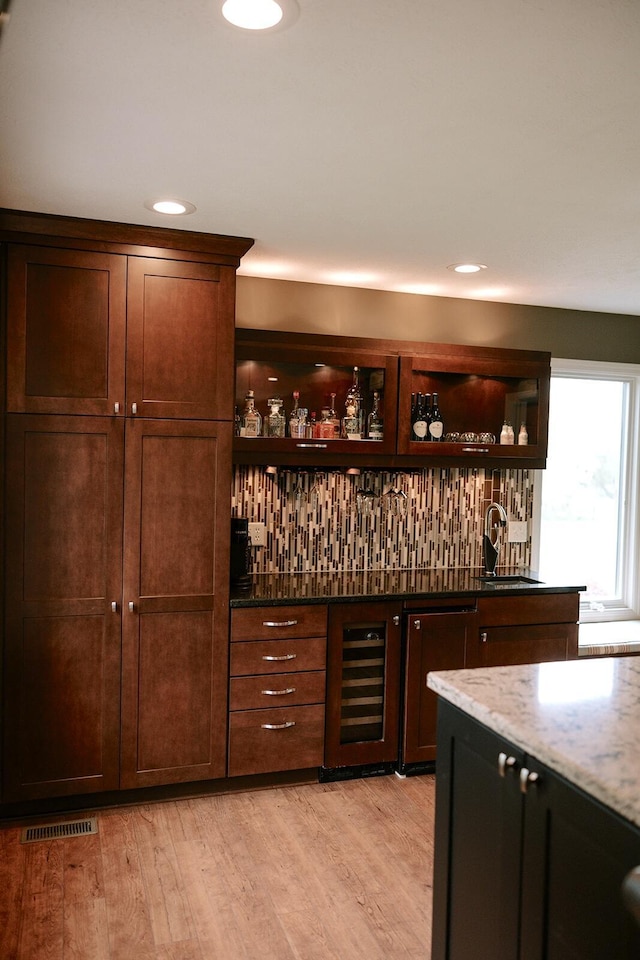 indoor wet bar with beverage cooler, light wood finished floors, and recessed lighting