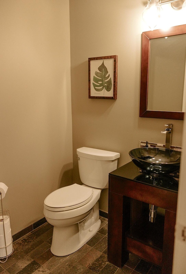 bathroom featuring baseboards, toilet, and vanity