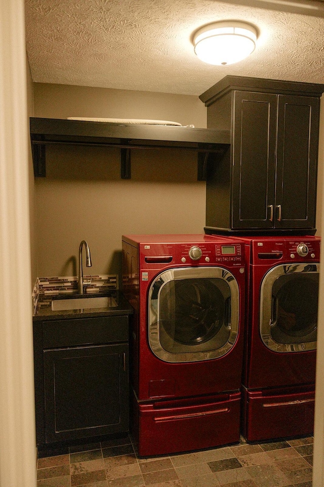 laundry room with independent washer and dryer, cabinet space, and a textured ceiling