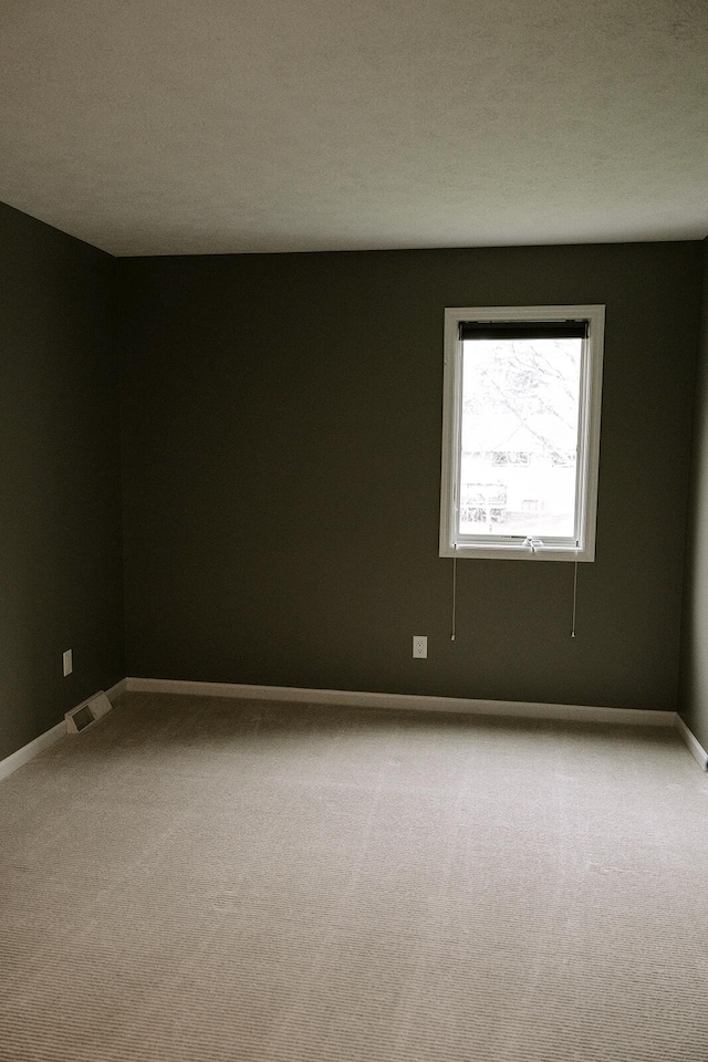 carpeted empty room featuring baseboards