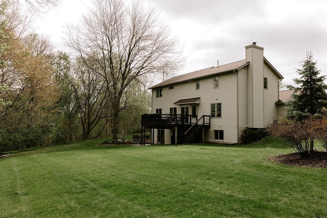 rear view of house with a chimney, a deck, a lawn, and stairs