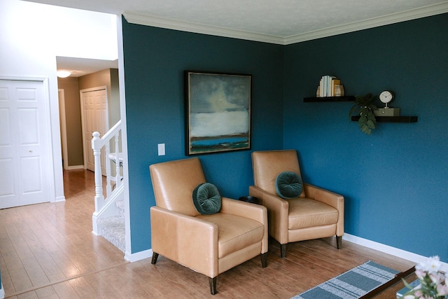 living area featuring stairway, wood finished floors, baseboards, and crown molding
