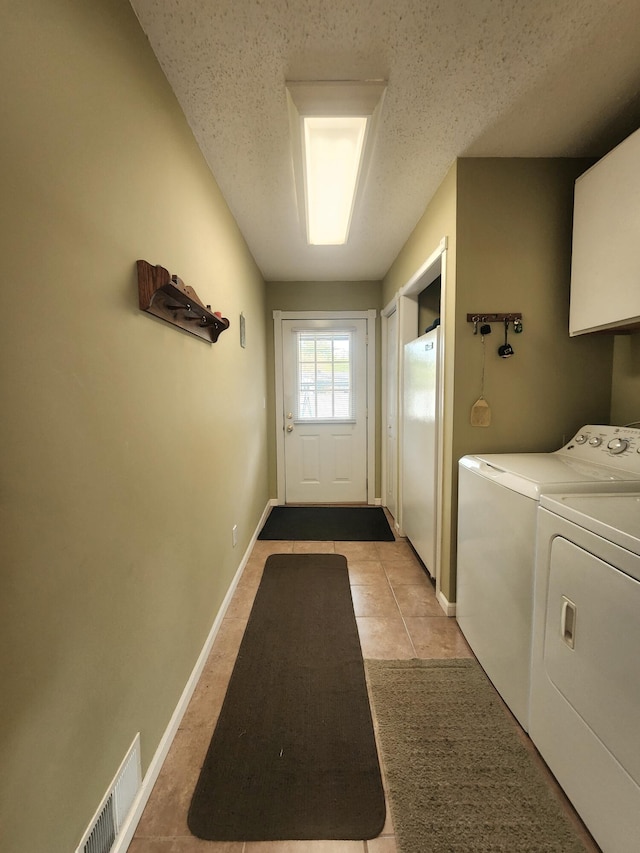 3034 Royalton Heights Rd, Saint Joseph, MI 49085 - laundry room with washing machine and clothes dryer, a textured ceiling, cabinet space, baseboards, and light tile patterned floors