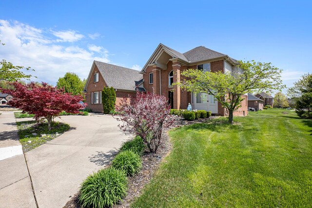 55796 Caesars Dr, Shelby Twp, MI 48315 - traditional home featuring brick siding, a front yard, concrete driveway, and a shingled roof