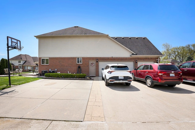 55796 Caesars Dr, Shelby Twp, MI 48315 - view of side of property featuring driveway, a garage, brick siding, roof with shingles, and cooling unit