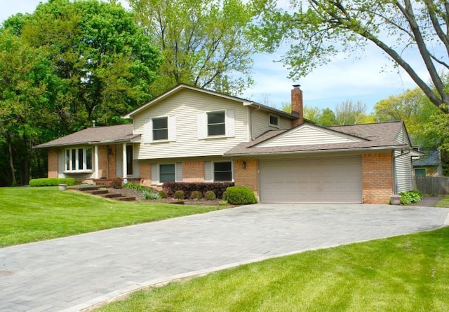 split level home featuring a chimney, a garage, brick siding, and driveway