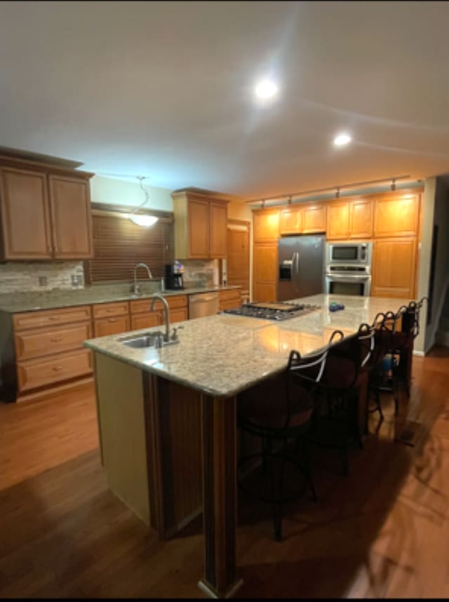 kitchen featuring stainless steel appliances, an island with sink, a sink, dark wood finished floors, and recessed lighting