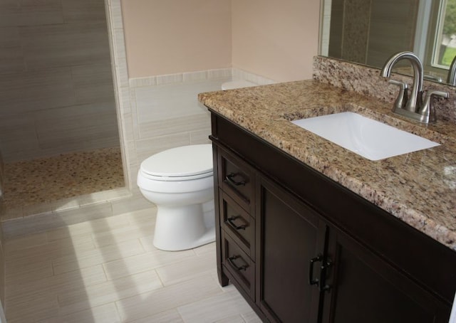 full bathroom featuring toilet, a tile shower, vanity, and tile patterned flooring