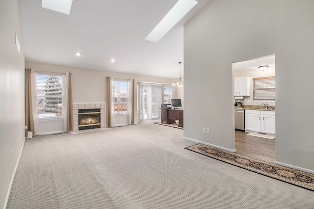 860 Woodhaven Dr, Commerce Twp, MI 48390 - unfurnished living room featuring a skylight, baseboards, light carpet, a tiled fireplace, and recessed lighting