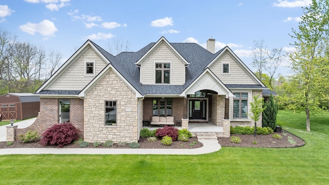 view of front facade with stone siding, a chimney, a shingled roof, and a front yard