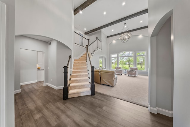 entrance foyer with beam ceiling, arched walkways, baseboards, a towering ceiling, and dark wood-style floors