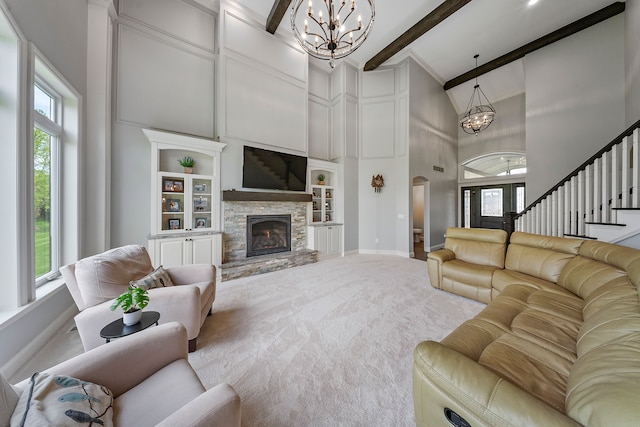 carpeted living room featuring a chandelier, high vaulted ceiling, built in shelves, baseboards, and plenty of natural light