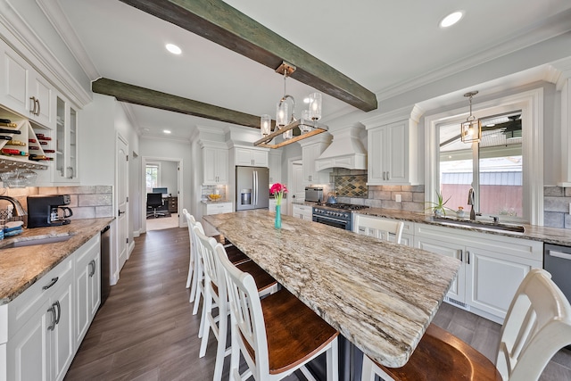kitchen featuring appliances with stainless steel finishes, custom exhaust hood, a sink, white cabinetry, and recessed lighting