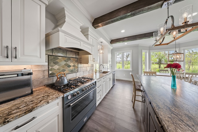 kitchen with stainless steel appliances, beamed ceiling, dark wood-type flooring, white cabinets, and dark stone countertops