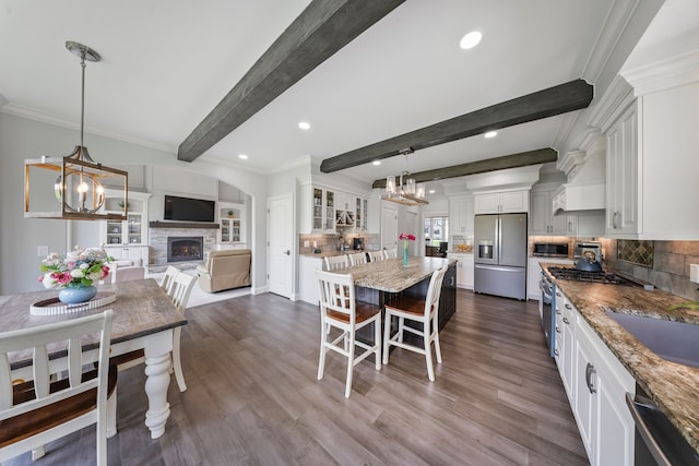 dining space featuring a stone fireplace, dark wood finished floors, beam ceiling, recessed lighting, and crown molding