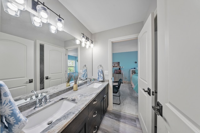 full bathroom with ensuite bathroom, double vanity, and wood finished floors