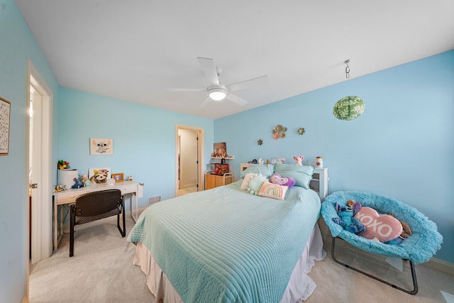 bedroom featuring light carpet, ceiling fan, an office area, and baseboards