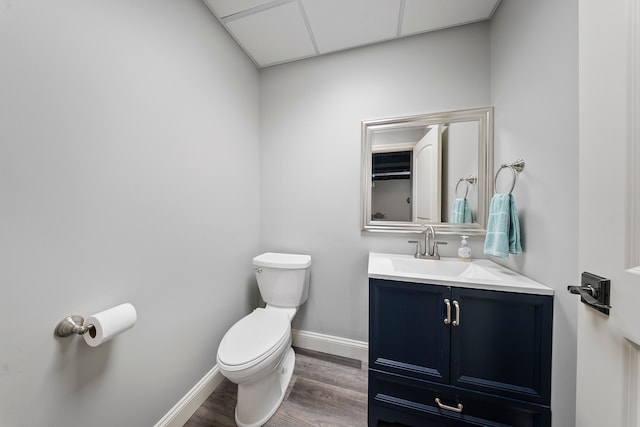 half bath with wood finished floors, toilet, baseboards, and vanity