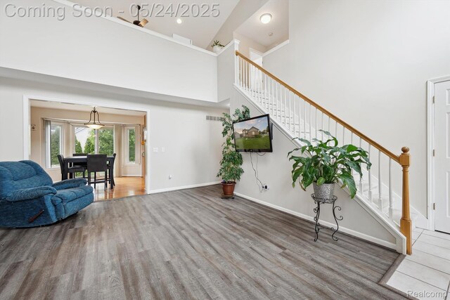 7366 Meadow Ln, Ypsilanti, MI 48197 - living room with wood finished floors, stairway, a high ceiling, and baseboards