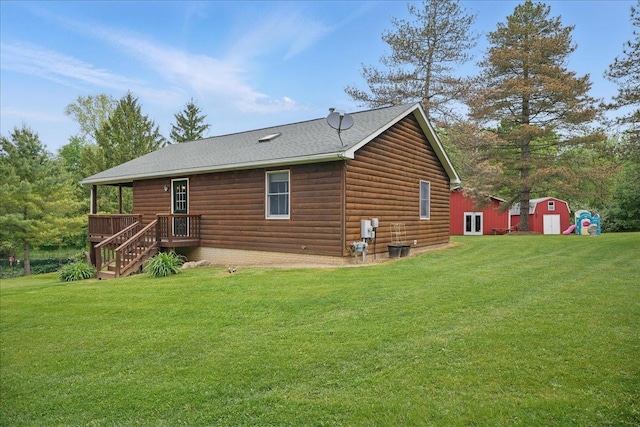 rear view of property with a lawn, faux log siding, a wooden deck, and roof with shingles