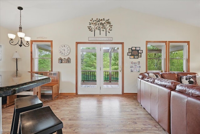 living room with vaulted ceiling, light wood-style floors, baseboards, and a chandelier