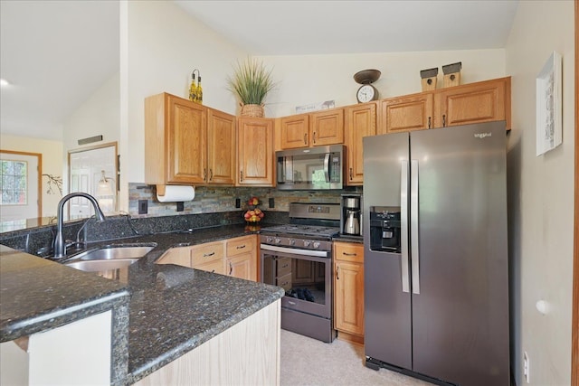 kitchen with stainless steel appliances, a sink, vaulted ceiling, a peninsula, and decorative backsplash