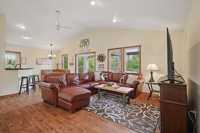 living room with lofted ceiling, wood finished floors, a ceiling fan, healthy amount of natural light, and baseboards