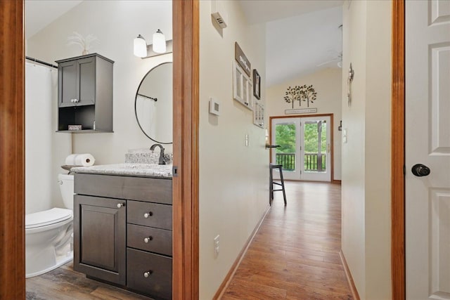 hallway with wood finished floors, lofted ceiling, a sink, and baseboards