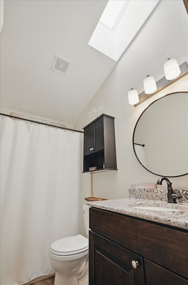 bathroom with a skylight, vaulted ceiling, toilet, and vanity