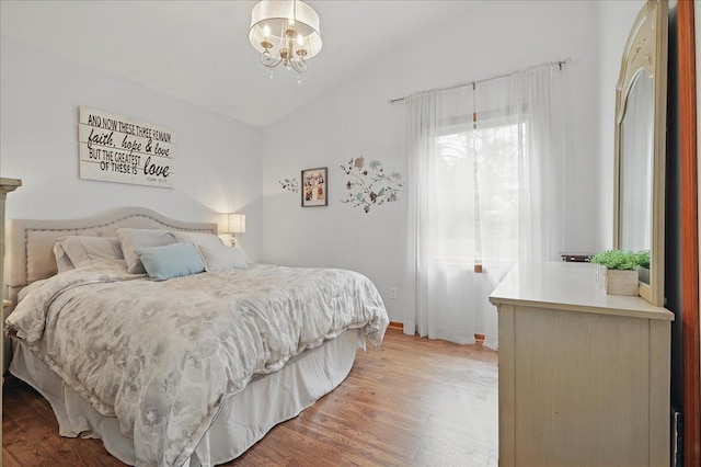 bedroom with vaulted ceiling, a chandelier, and wood finished floors