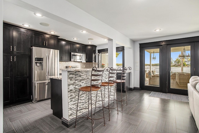 kitchen with appliances with stainless steel finishes, french doors, a breakfast bar, plenty of natural light, and recessed lighting