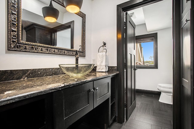 bathroom with baseboards, toilet, and vanity