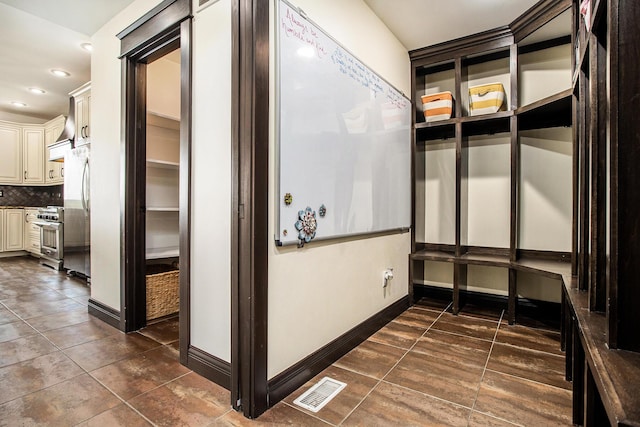 hall with recessed lighting, dark tile patterned flooring, and baseboards