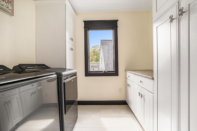 laundry room with washer and clothes dryer, cabinet space, baseboards, and light tile patterned flooring