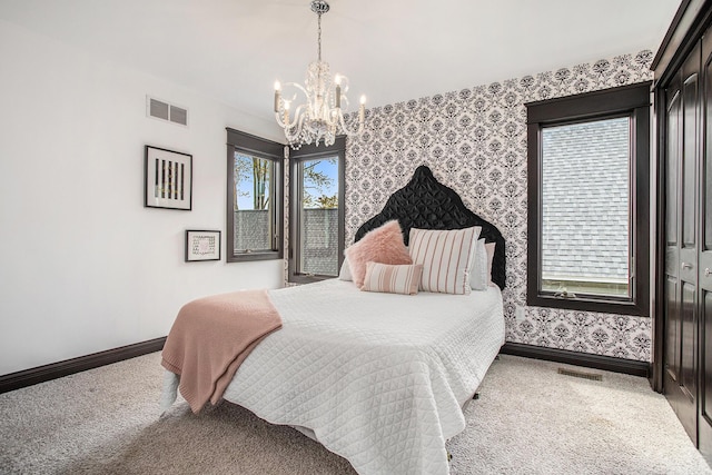 carpeted bedroom with wallpapered walls, a chandelier, and baseboards