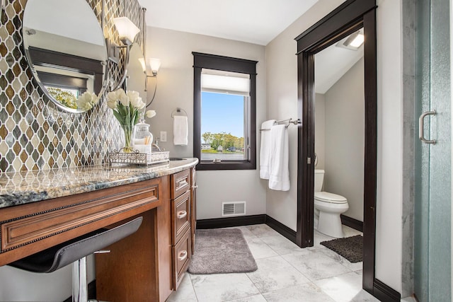 bathroom with toilet, plenty of natural light, vanity, and baseboards