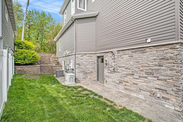 view of home's exterior featuring stone siding and central AC