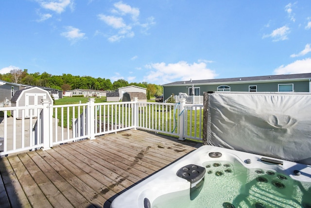 wooden deck featuring a storage unit, an outdoor structure, a hot tub, and a yard